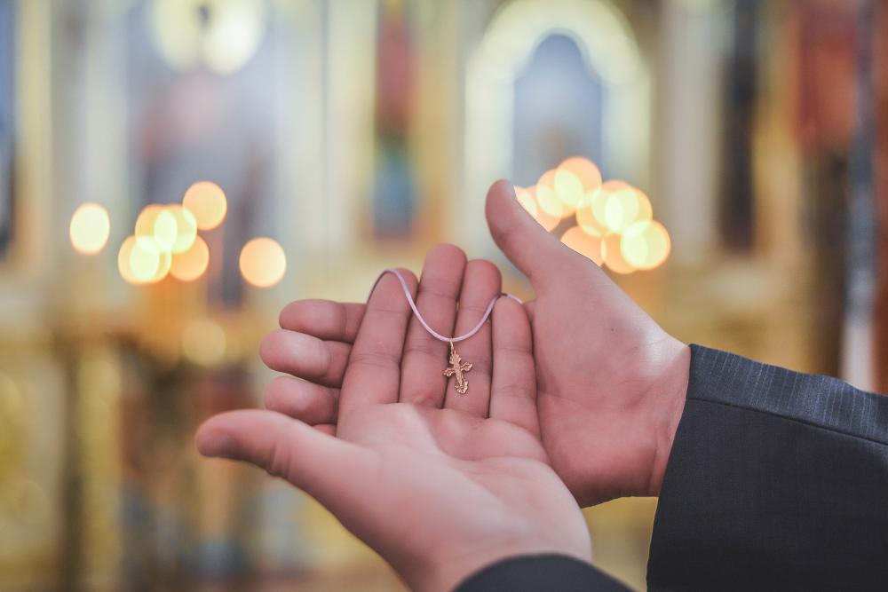 mains tenant un collier avec une croix